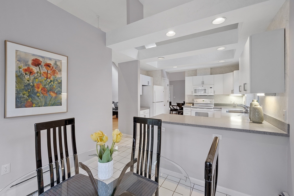 34 Pickman Drive, Unit 34 Bedford, MA 01730 - Photo 21 of 38 a kitchen with stainless steel appliances wooden floor dining table and chairs