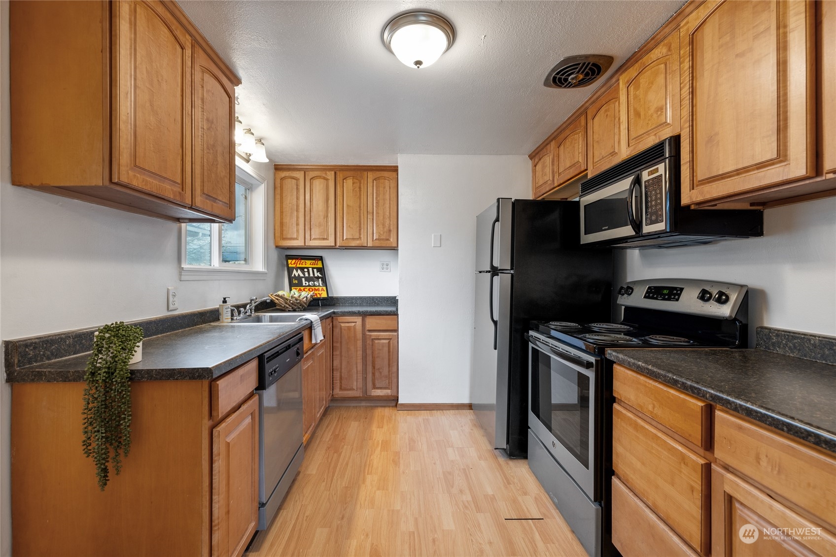 5037 South State Street Tacoma, WA 98409 - Photo 11 of 40 a kitchen with stainless steel appliances granite countertop a stove a sink dishwasher a refrigerator and cabinets with wooden floor