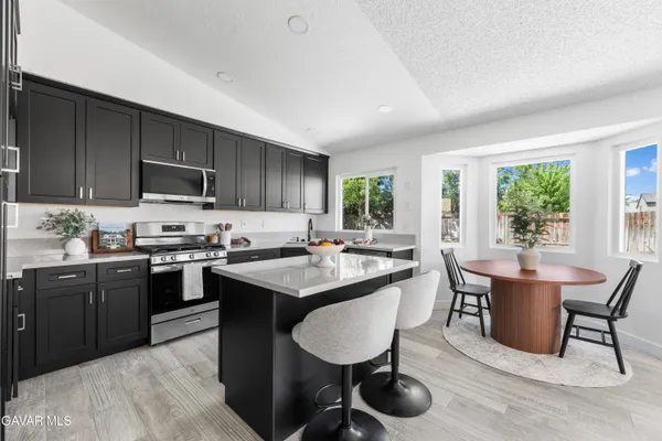 a kitchen with stainless steel appliances granite countertop wooden cabinets a dining table and chairs