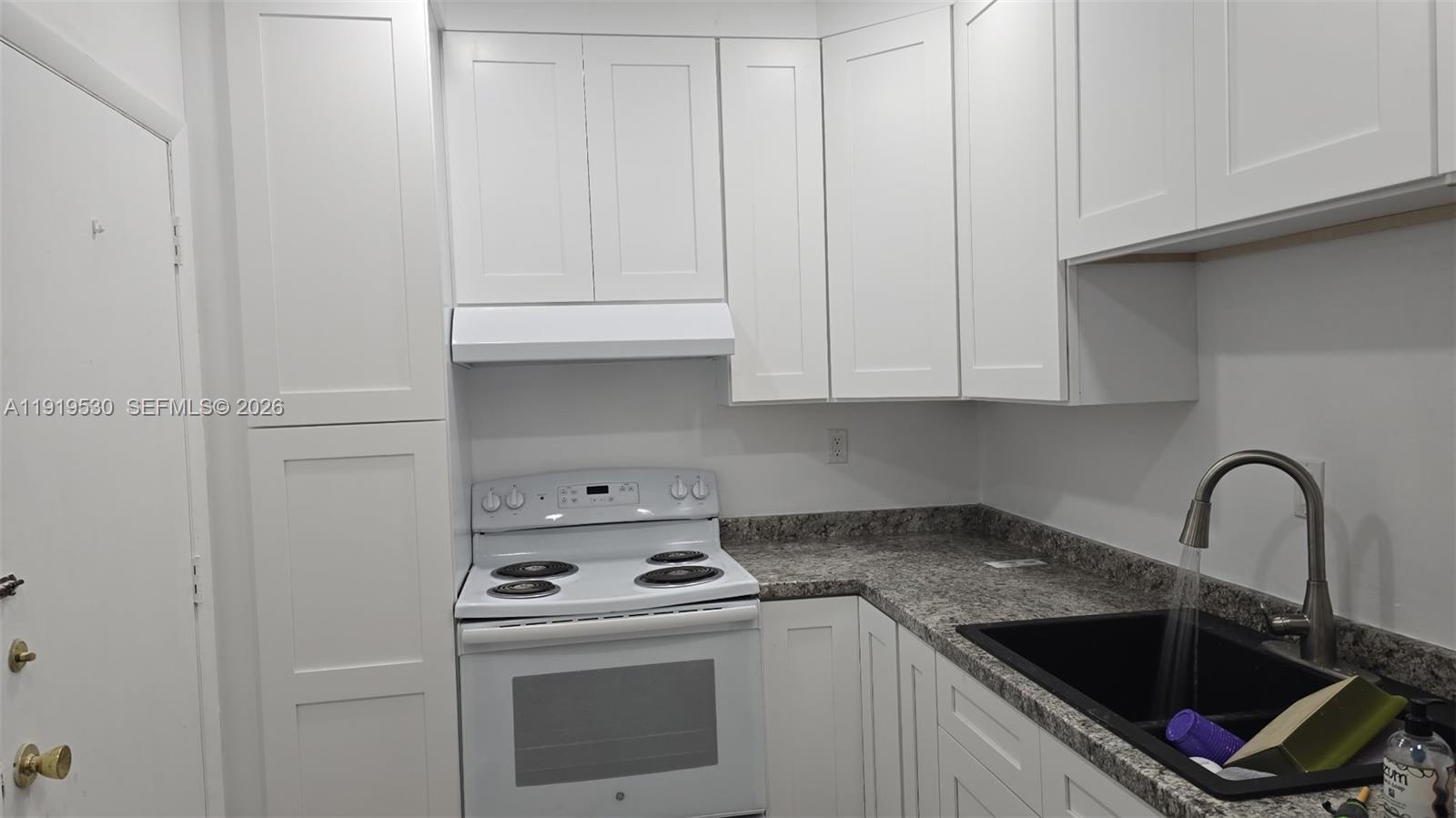9159 Southwest 77th Avenue, Unit 211 Miami, FL 33156 - Photo 2 of 9 a kitchen with granite countertop white cabinets and sink