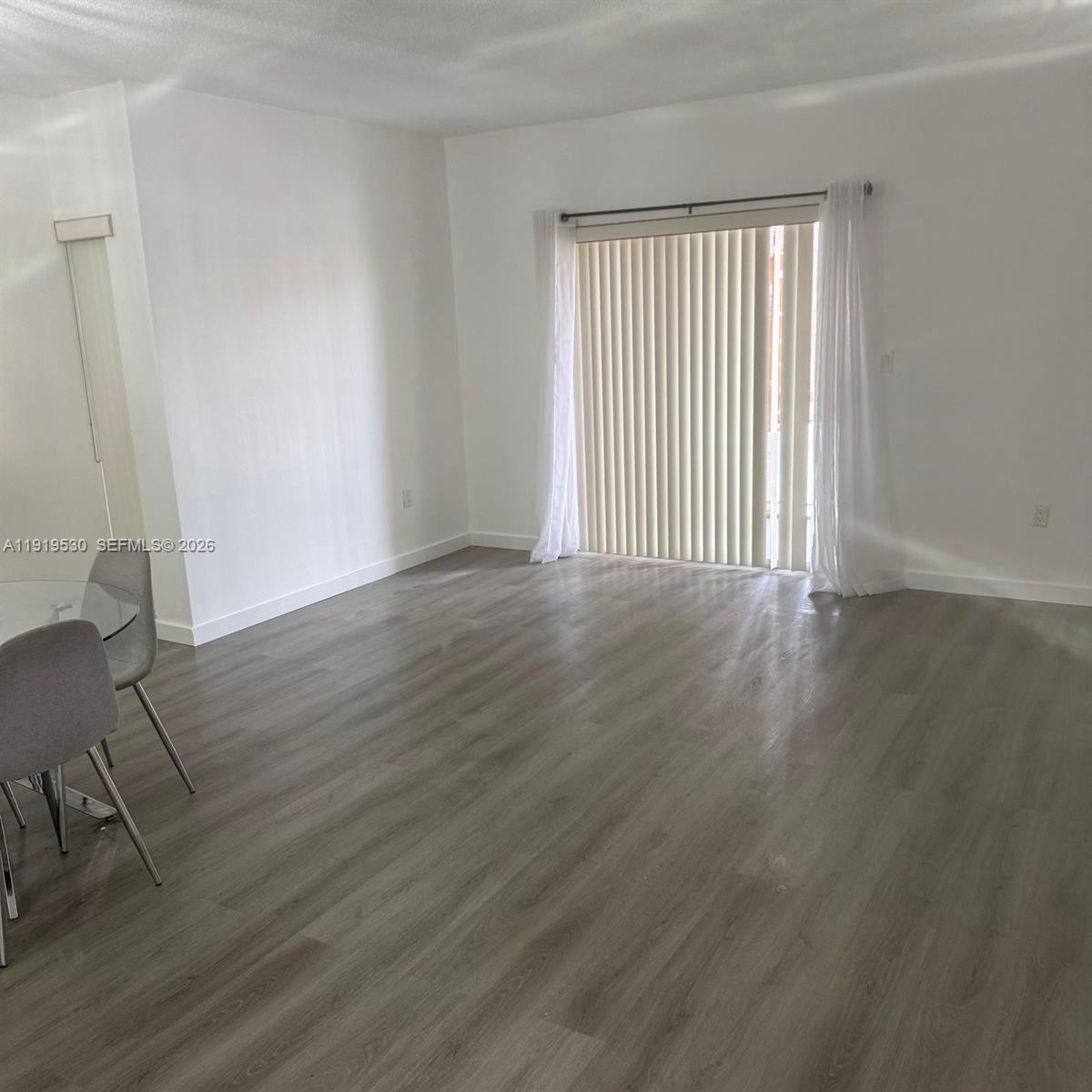 9159 Southwest 77th Avenue, Unit 211 Miami, FL 33156 - Photo 4 of 9 a view of an empty room with wooden floor and a window