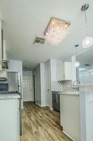 a kitchen with kitchen island granite countertop stainless steel appliances a counter space and a chandelier