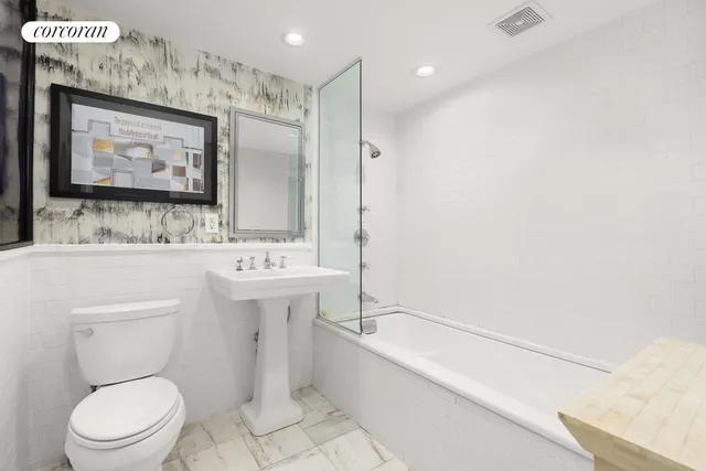 a bathroom with a toilet a sink a mirror and a bathtub