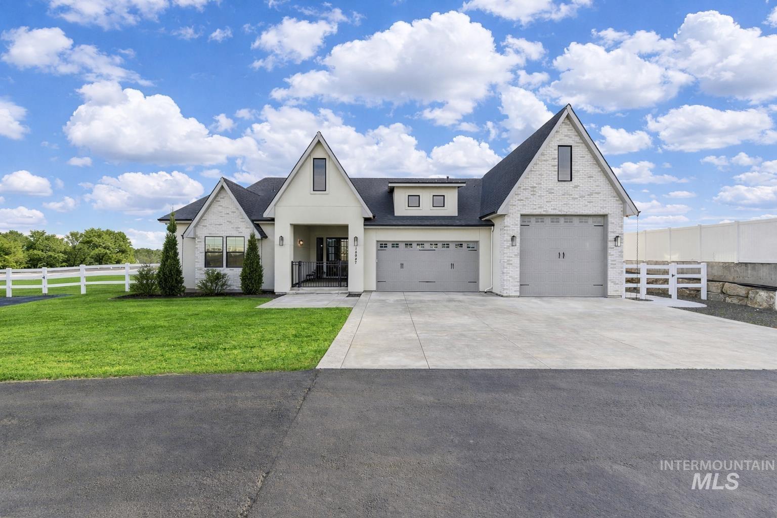 Modern farmhouse featuring driveway, a shingled roof, and an attached garage