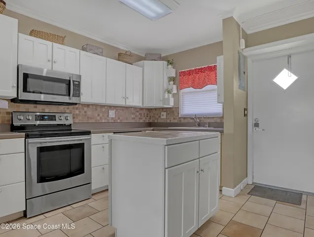a kitchen with granite countertop white cabinets stainless steel appliances and a window