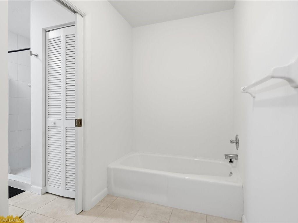 1833 Courtyard Way, Unit E105 Naples, FL 34112 - Photo 15 of 28 Full bathroom with a closet, tiled shower, light tile patterned floors, and a tub to relax in