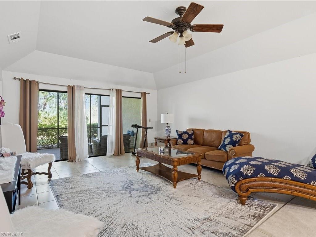 1833 Courtyard Way, Unit E105 Naples, FL 34112 - Photo 2 of 28 Living area with vaulted ceiling, light tile patterned floors, and ceiling fan