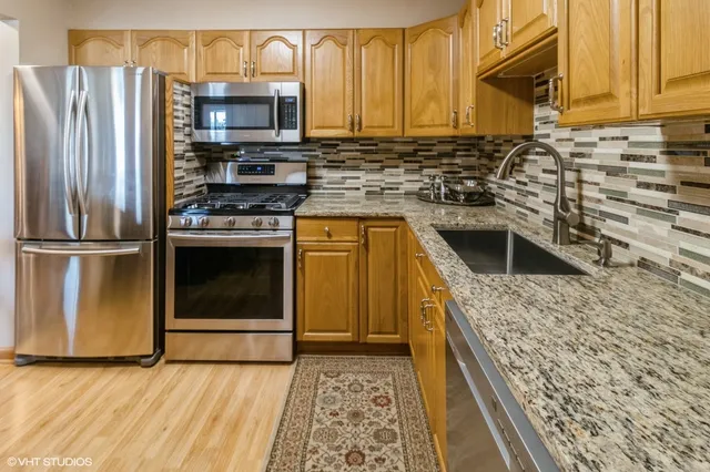 a kitchen with stainless steel appliances granite countertop a stove a sink and a microwave