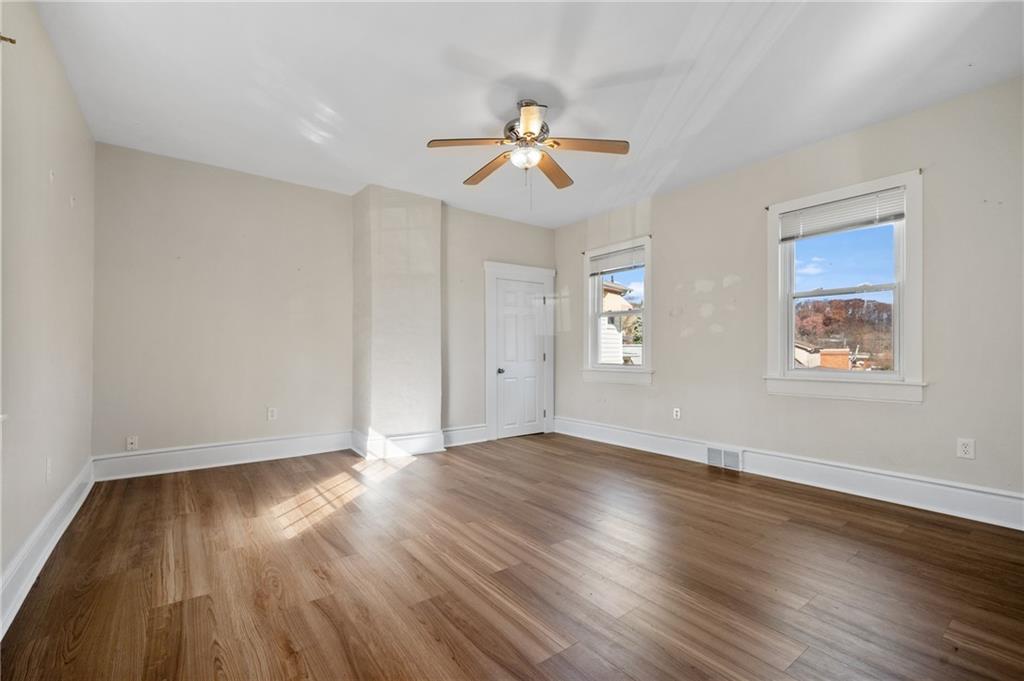320 Newkirk Avenue Carnegie, PA 15106 - Photo 12 of 25 an empty room with wooden floor a ceiling fan and windows