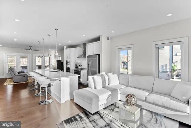a living room with furniture kitchen view and a large window