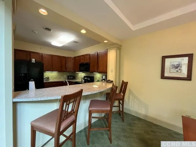 a kitchen with stainless steel appliances granite countertop a dining table chairs and a refrigerator