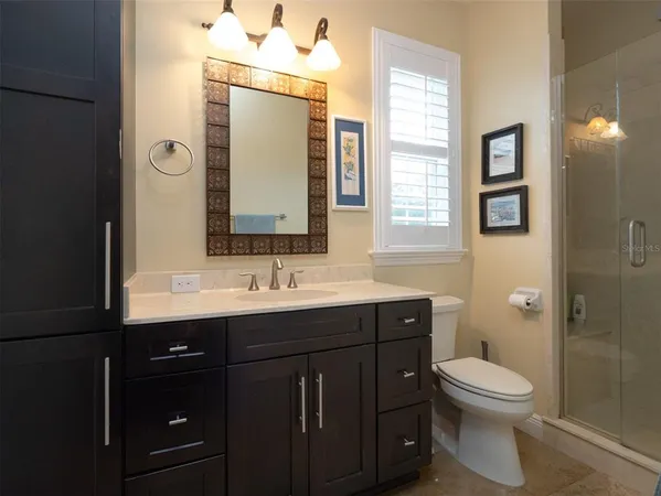 a bathroom with a toilet a sink a mirror a window and vanity