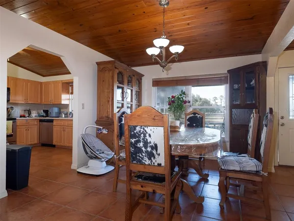 a view of a dining room with furniture a chandelier and kitchen view