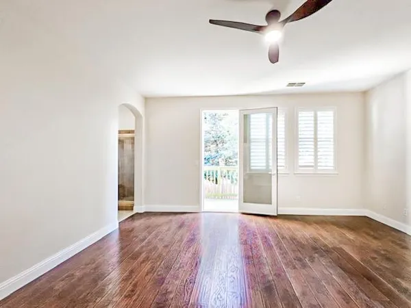 an empty room with wooden floor and windows