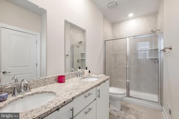 a bathroom with a granite countertop sink a toilet and shower