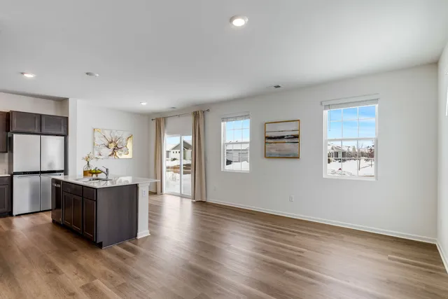 a living room with stainless steel appliances kitchen island hardwood floor and window