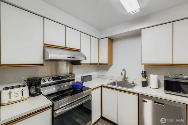 a kitchen with stainless steel appliances a sink dishwasher stove and cabinets