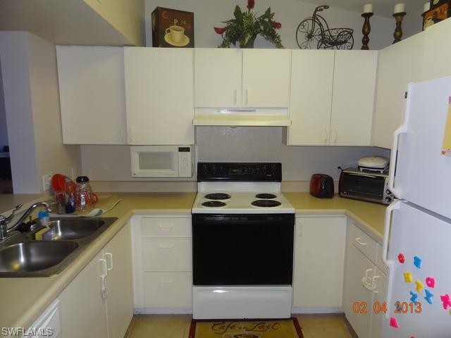 8284 Key Royal Circle, Unit 1332 Naples, FL 34119 - Photo 3 of 13 a kitchen with a sink a stove and cabinets
