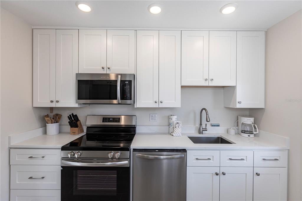 6020 Midnight Pass Road, Unit 15 Sarasota, FL 34242 - Photo 10 of 19 a kitchen with stainless steel appliances granite countertop a sink a stove and a microwave