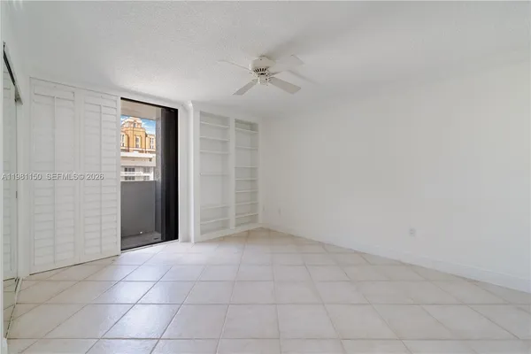 an empty room with a ceiling fan and glass door