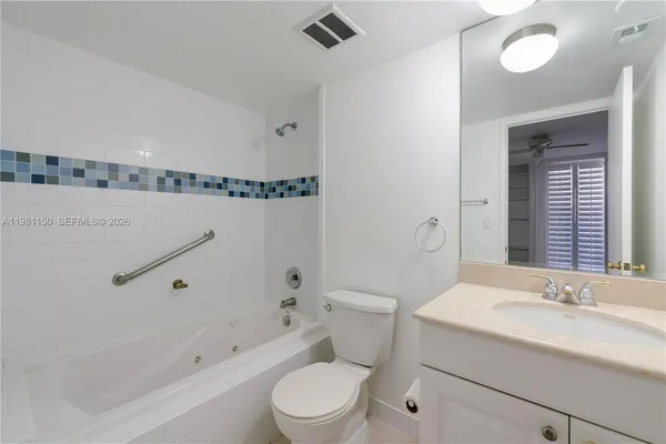 a bathroom with a granite countertop sink mirror vanity and toilet