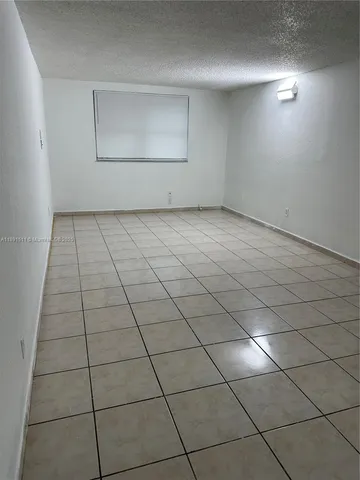 a view of a refrigerator in kitchen and an empty room