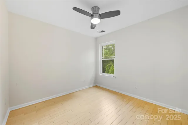 an empty room with a window and a ceiling fan