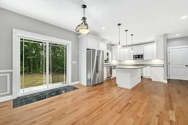 a open kitchen with stainless steel appliances granite countertop a refrigerator a stove a sink dishwasher a refrigerator and white cabinets with wooden floor