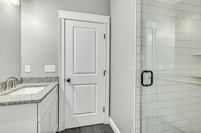 a bathroom with a granite countertop sink a mirror and shower
