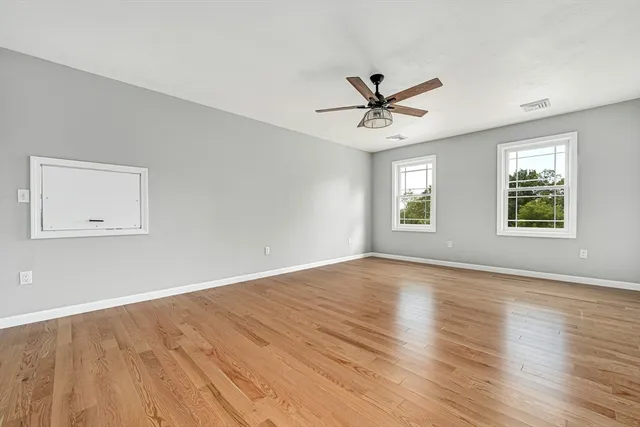 a view of an empty room with window and wooden floor