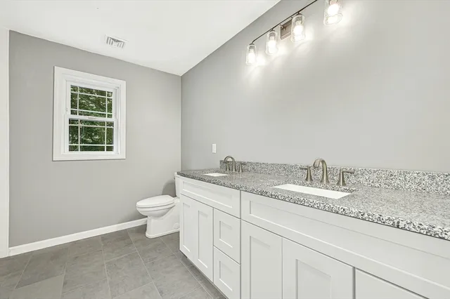 a bathroom with a granite countertop sink and a toilet
