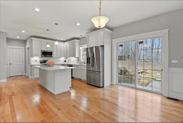 a kitchen with stainless steel appliances kitchen island granite countertop a refrigerator oven a sink dishwasher and a wooden cabinets