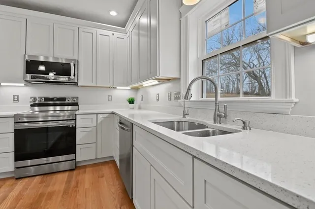 a kitchen with granite countertop a sink stainless steel appliances and cabinets
