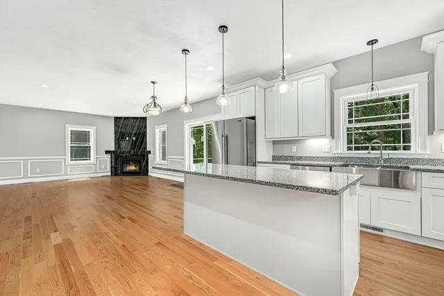 a kitchen with stainless steel appliances granite countertop a sink a refrigerator a stove and a wooden floors