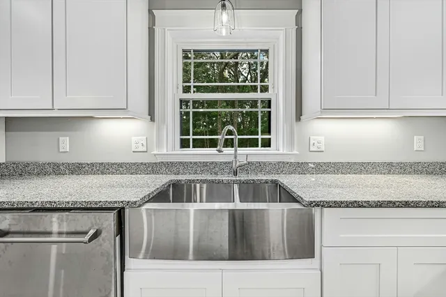 a kitchen with granite countertop a sink window and cabinets