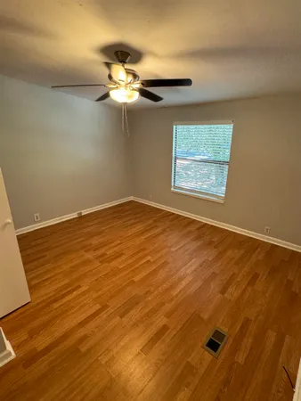 a view of a room with wooden floor and a ceiling fan