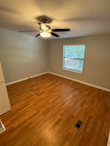 a view of a room with wooden floor and a ceiling fan