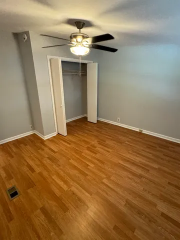 an empty room with wooden floor and chandelier fan