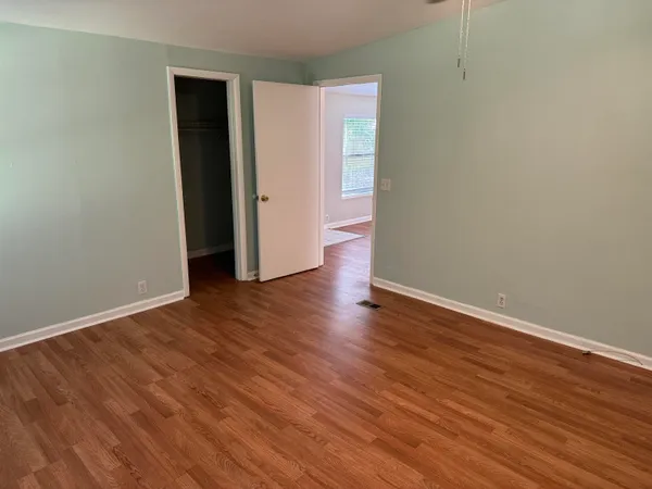 a view of an empty room with wooden floor and closet
