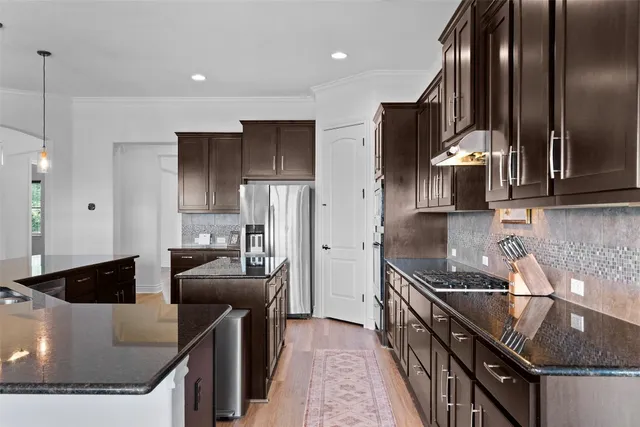 a kitchen with stainless steel appliances granite countertop a sink a stove and a refrigerator