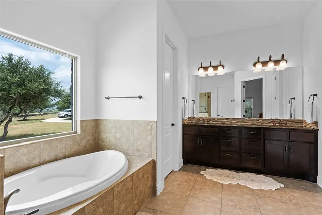 a spacious bathroom with a tub sink and mirror