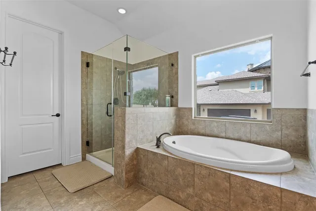 a bathroom with a tub a mirror and a shower