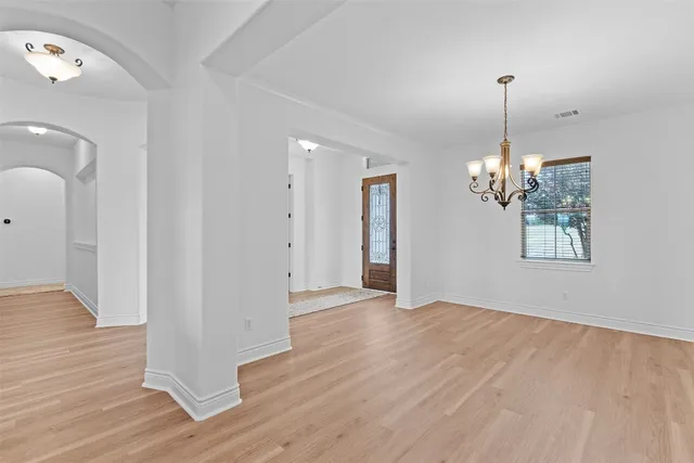 a view of a room with wooden floor chandelier and windows