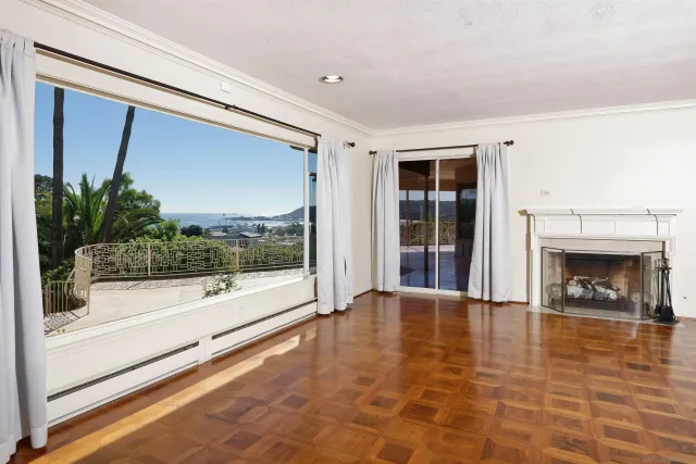 a view of empty room with floor to ceiling window and fireplace