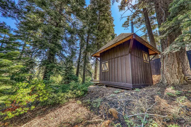 a view of barn with large trees and wooden fence
