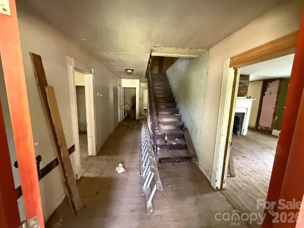 a view of a hallway with wooden floor and stairs