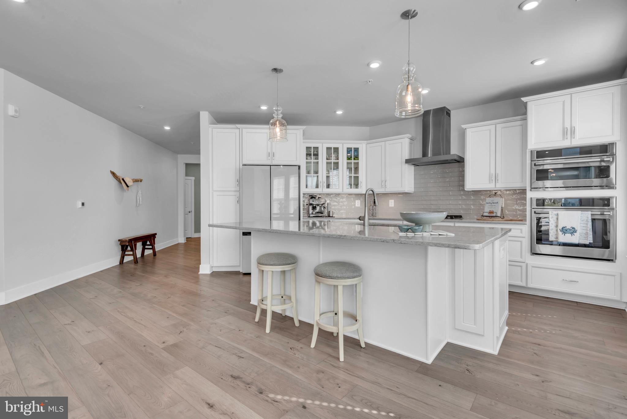 111 Marshgrass Way, Unit 21 Chester, MD 21619 - Photo 15 of 57 a kitchen with stainless steel appliances granite countertop a stove a sink a refrigerator and a dining table with wooden floor