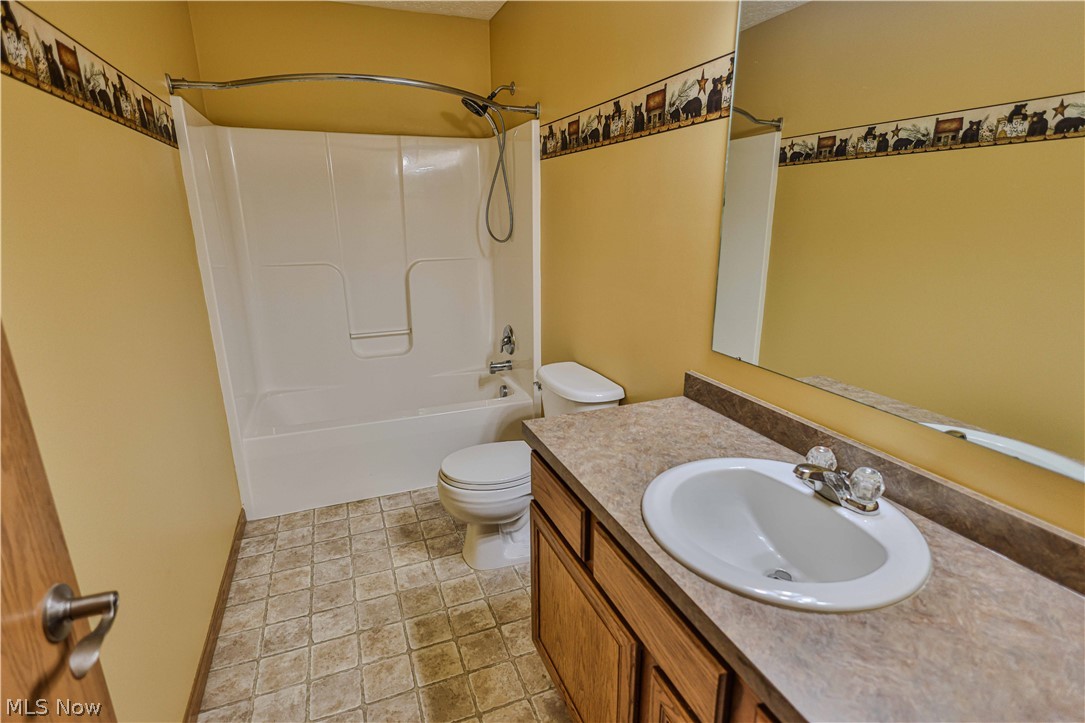11154 Johnsford Road Southwest Beach City, OH 44608 - Photo 46 of 50 Full bathroom featuring a shower-over-tub combination, a vanity with an integrated sink, a large wall-mounted mirror, wood-finish cabinetry, and patterned floor tiling