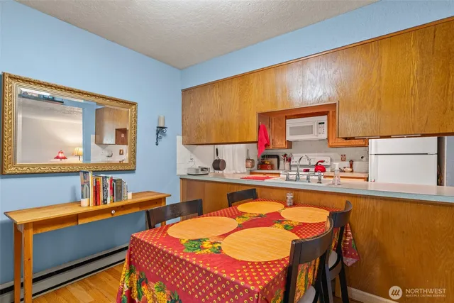 a kitchen with stainless steel appliances kitchen island granite countertop a table chairs in it and a wooden floor