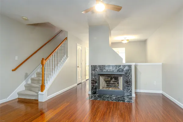 a view of an empty room with wooden floor fireplace and a window